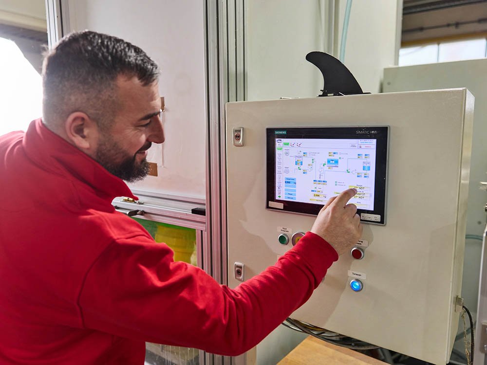 Bedienung der Anlagensteuerung für Gieß-Elastomer Prozesse Mitarbeiter bedient ein Touchpanel an einer Produktionsanlage