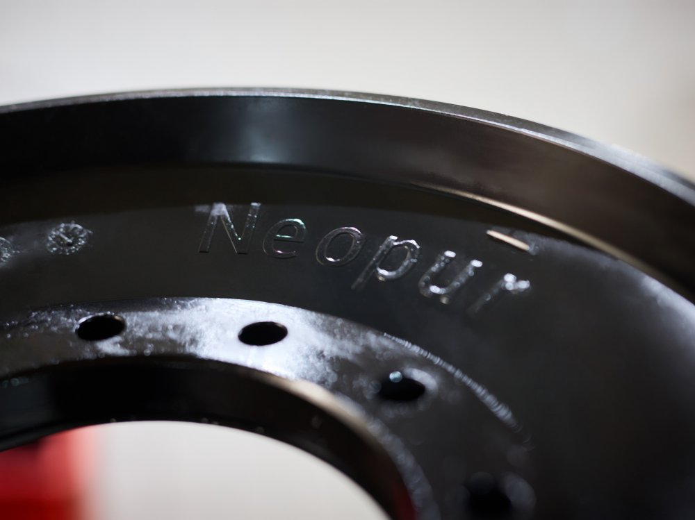 Gieß-Elastomer Formteil mit eingeprägter NEOPUR Kennzeichnung Detailaufnahme eines schwarzen Polyurethan-Formteils mit NEOPUR Prägung